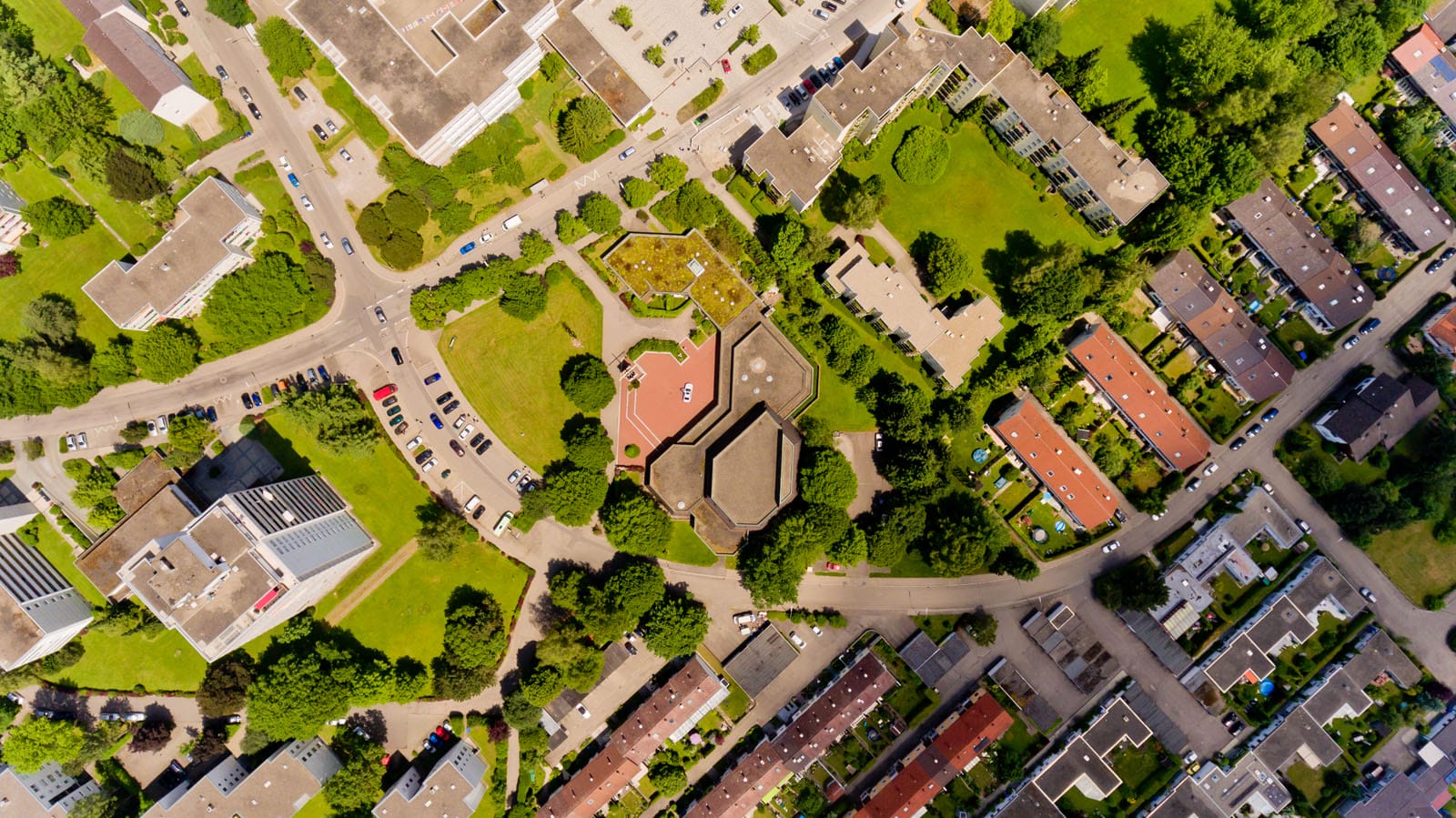 A top down view of a busy developing area with lots of green and houses.
