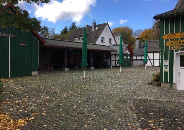 Ansicht der neu gestalteten Freianlagen des Heimatmuseums in Reichshof, mit Sitzgelegenheiten und Grünflächen für die Nach